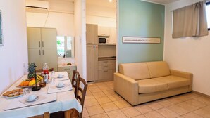 A compact living space with a dining area, kitchenette, and a sofa. - Lovely apartment in villa for 5 guests with A/C, pool, WIFI, TV and terrace (Rosolina)