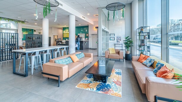 A spacious lobby with a bar area, seating arrangements, and large windows offering a view of the outside. - Break & Home Paris Italie Porte De Choisy (Ivry-sur-Seine)