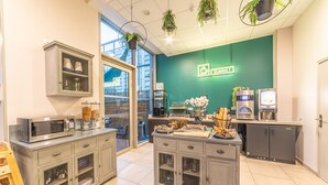 A modern kitchen with stainless steel appliances, a green accent wall, and a view of the city through large windows. - Break & Home Paris Italie Porte De Choisy (Ivry-sur-Seine)