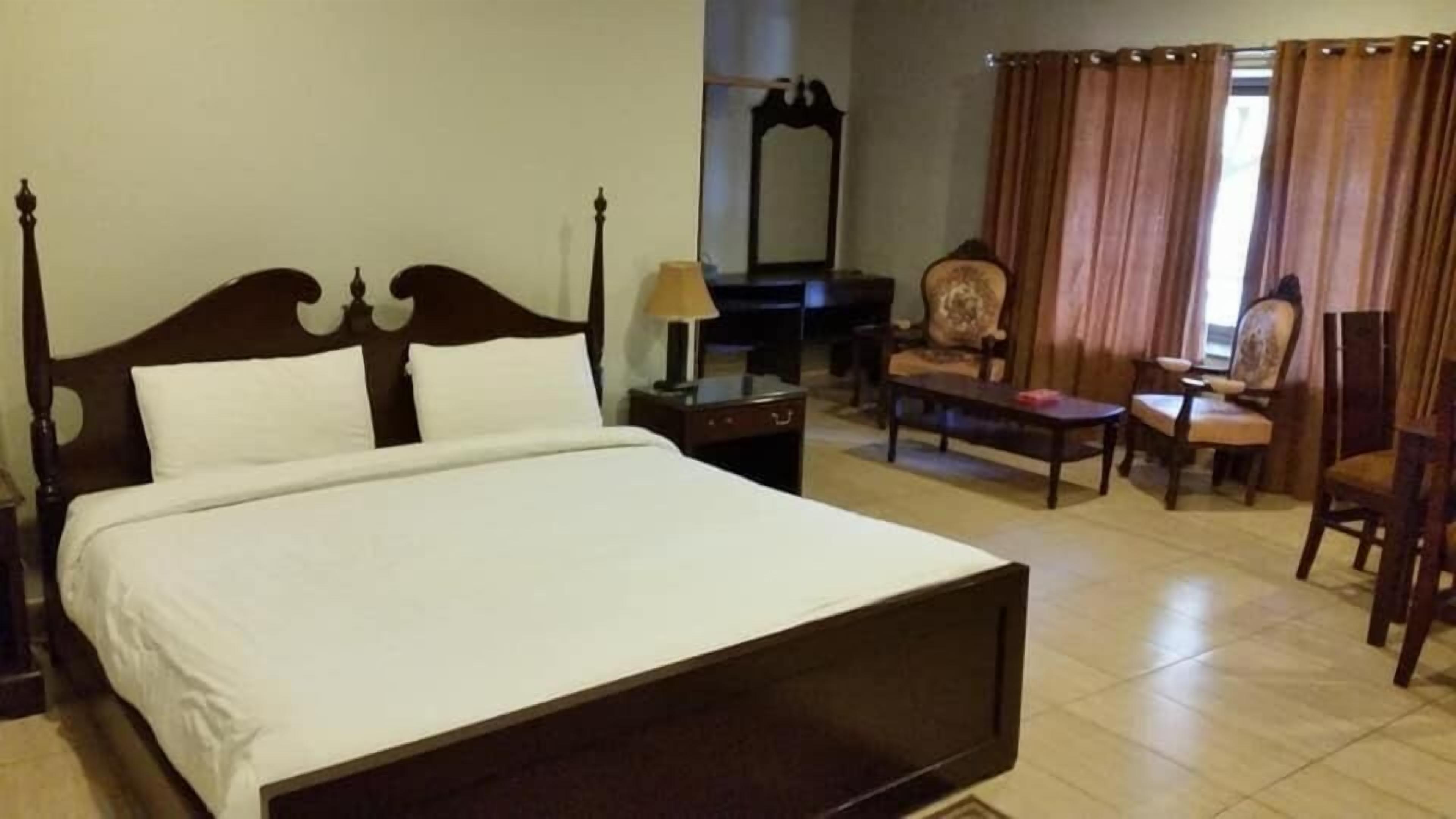 Habitación de hotel con una cama grande, un escritorio, una silla y un espejo.