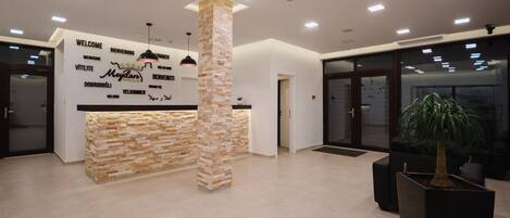 A reception area with a stone column, a reception desk, and a potted plant.