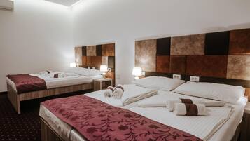 A hotel room with two beds, each with a headboard, bedside tables, lamps, and neatly made beds with towels.