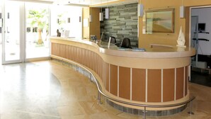 Un área de recepción con mostrador curvo, pared de piedra y puerta de vidrio que da al exterior.