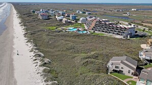 An aerial view of a coastal resort with multiple buildings, a beach, and a swimming pool. - Ocean View Delight, Resort Pools, Private Boardwalk | MP301 (Port Aransas)