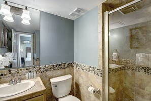 Een badkamer met een wastafel met twee kommen, toilet en een douchecabine van glas.