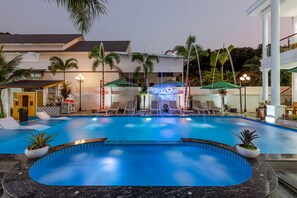 Een buitenzwembad, ligstoelen bij het zwembad