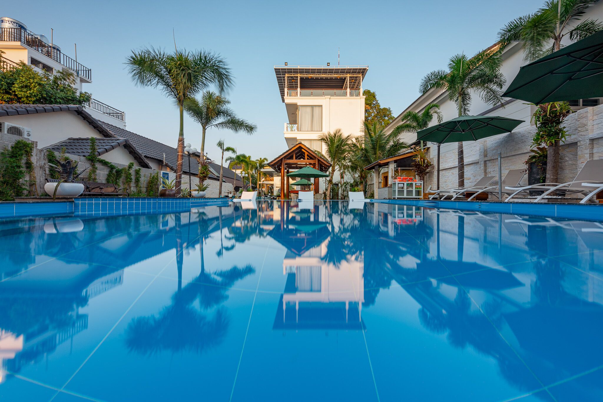 Una piscina con vistas claras al área de la piscina, incluyendo sillones y sombrillas.