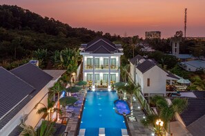 A large swimming pool with a view of a modern house and surrounding greenery.