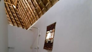 Un corridoio stretto con soffitto in bambù, un piccolo specchio appeso e una ringhiera.