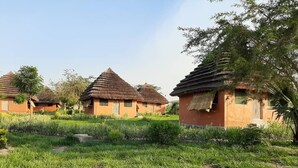 File di tradizionali capanne con tetti di paglia, immerse in prati curati e alberi.