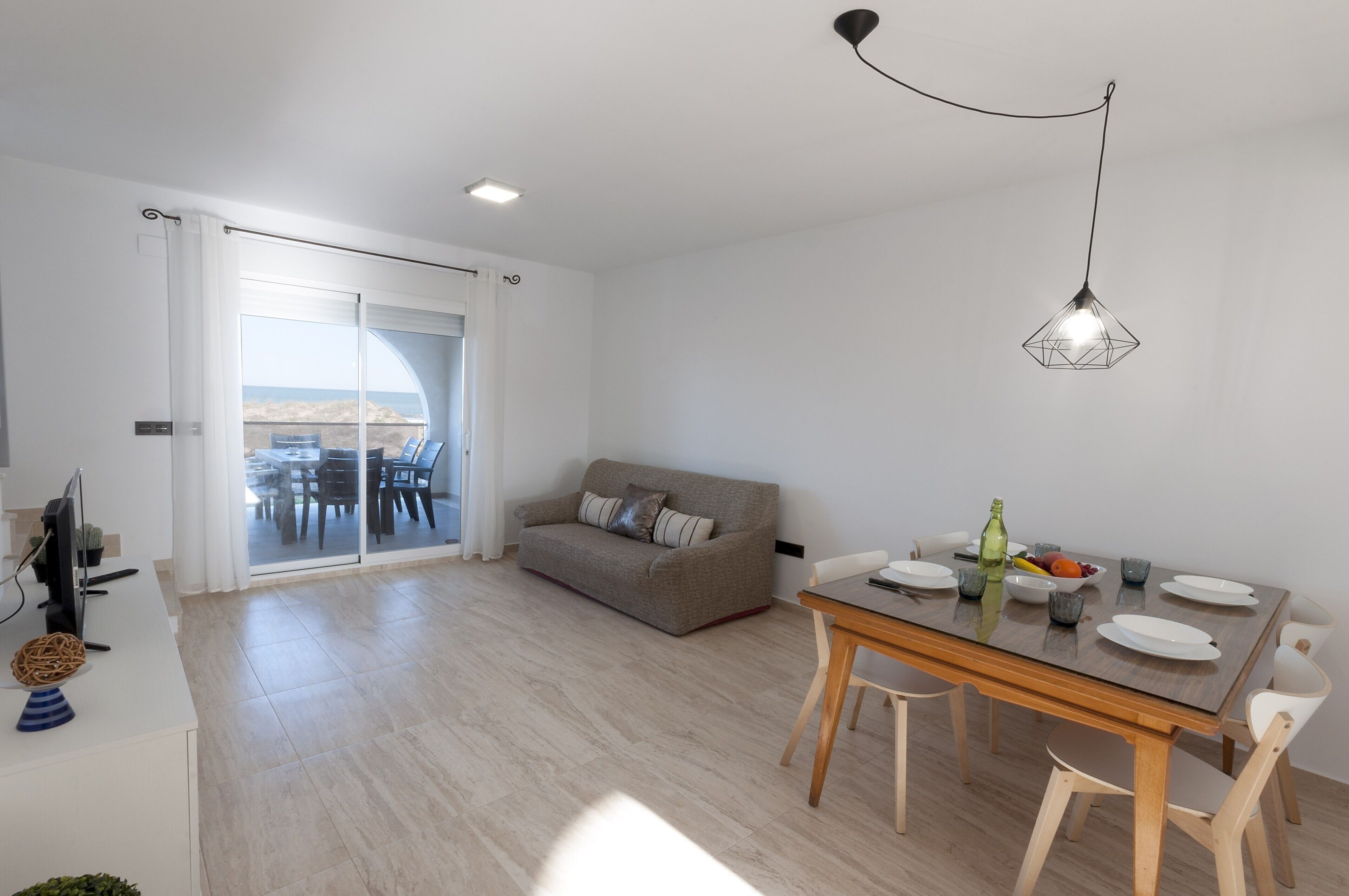 Una sala moderna con comedor, un sofá y vistas a través de un ventanal.