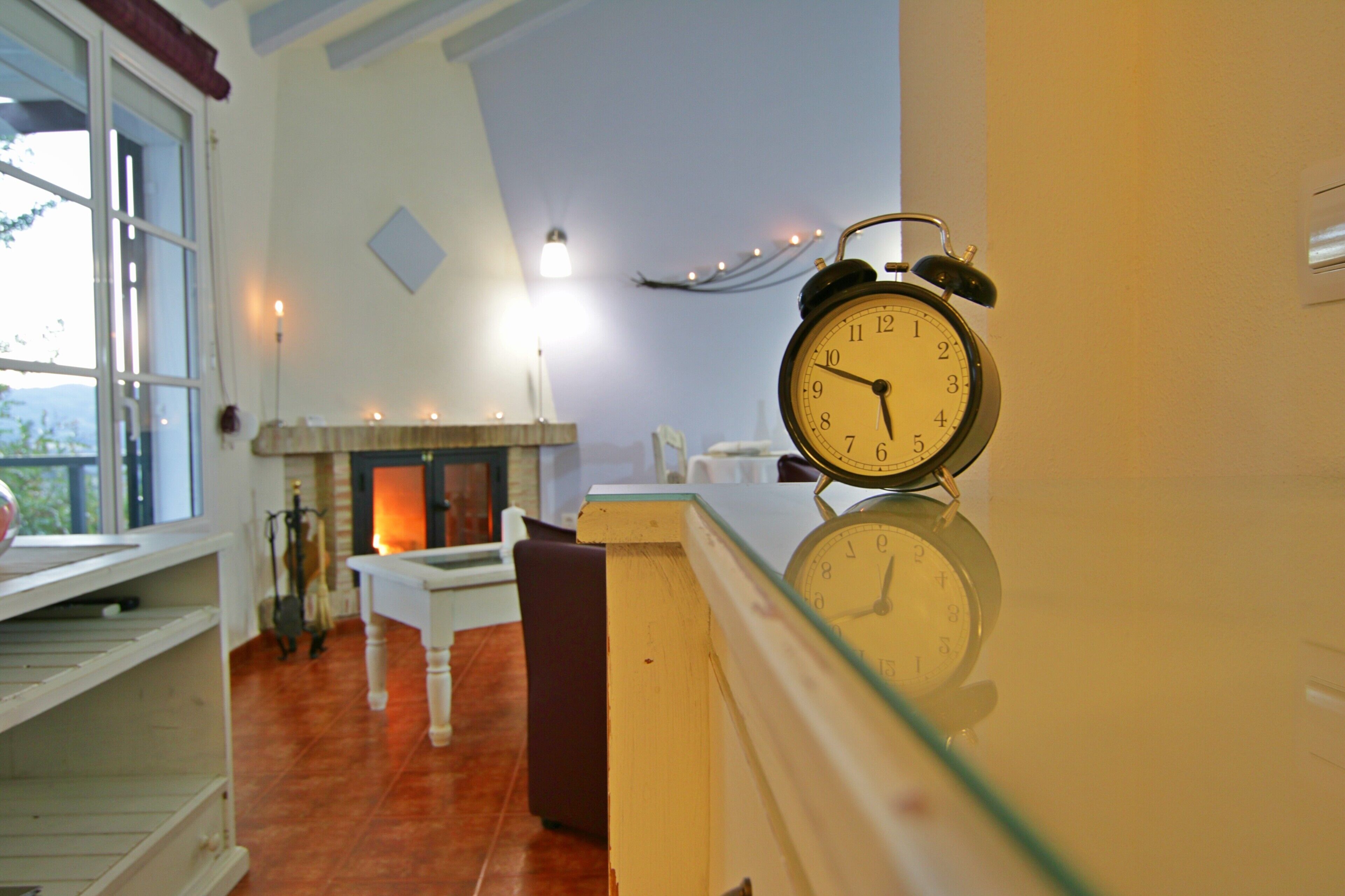 A room with a fireplace, a clock, and a view through a window.