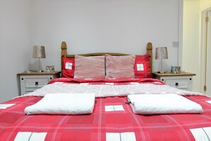 Un lit bien fait, recouvert d’une couverture à carreaux rouges et blancs, avec deux oreillers et deux serviettes blanches pliées.