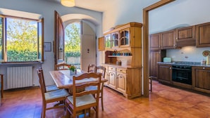 Una cucina con mobili in legno, un tavolo da pranzo con sedie e vista sul verde.