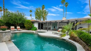 A swimming pool with a curved edge, surrounded by a patio area with outdoor furniture and palm trees. - LQ001 - 3 bedroom 3 bath with pool (La Quinta)