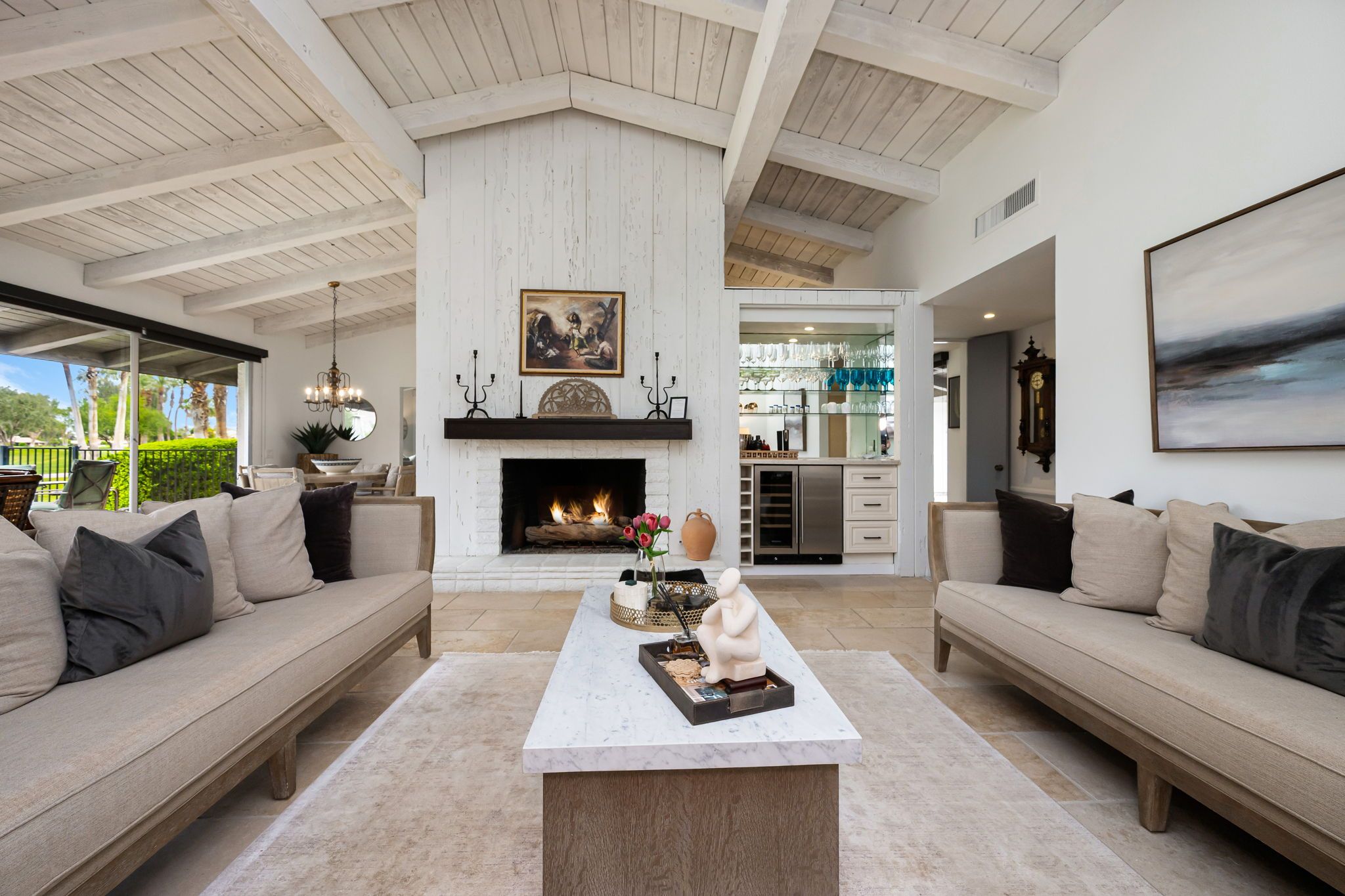 A spacious living room with high ceilings, a fireplace, and a view of the outdoors.