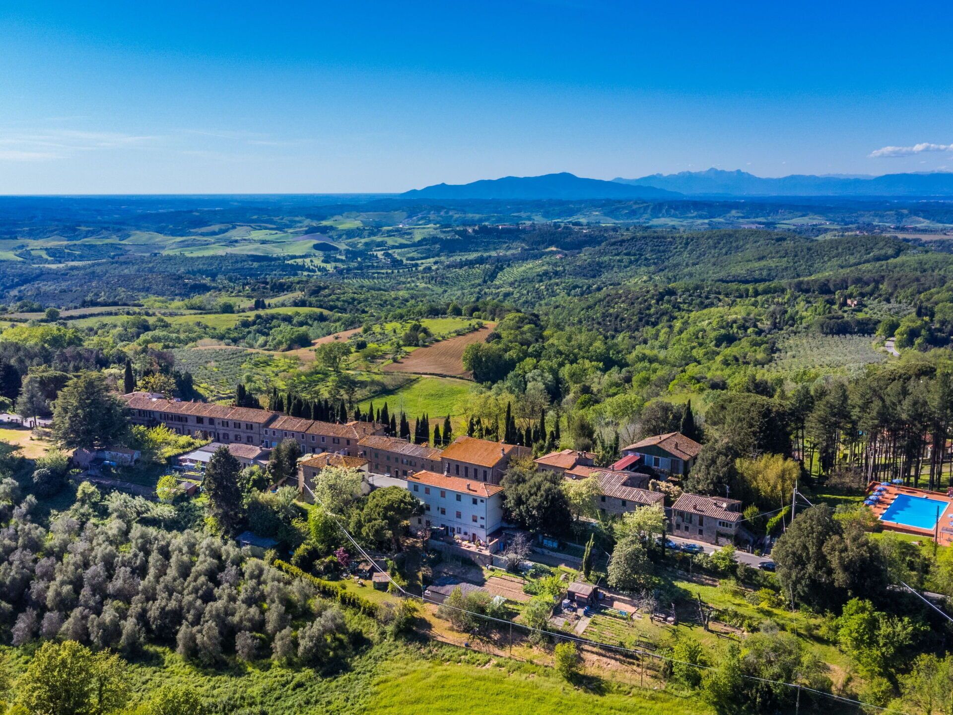 A villa with a swimming pool, surrounded by lush greenery and hilly terrain.