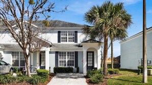 A two-story house with a front porch, a garage, and a driveway. - Windsor Hills 3 Bedroom Private Pool Townhome (Kissimmee)