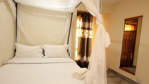 A bed with a canopy, a mirror, and a patterned curtain. - Guest House in Arusha -Nanofilter Family (Arusha)