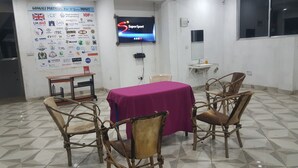 A conference room with a round table covered by a purple tablecloth, surrounded by four wooden chairs. A television screen displays the "SuperSport" logo. - Guest House in Arusha -Nanofilter Family (Arusha)