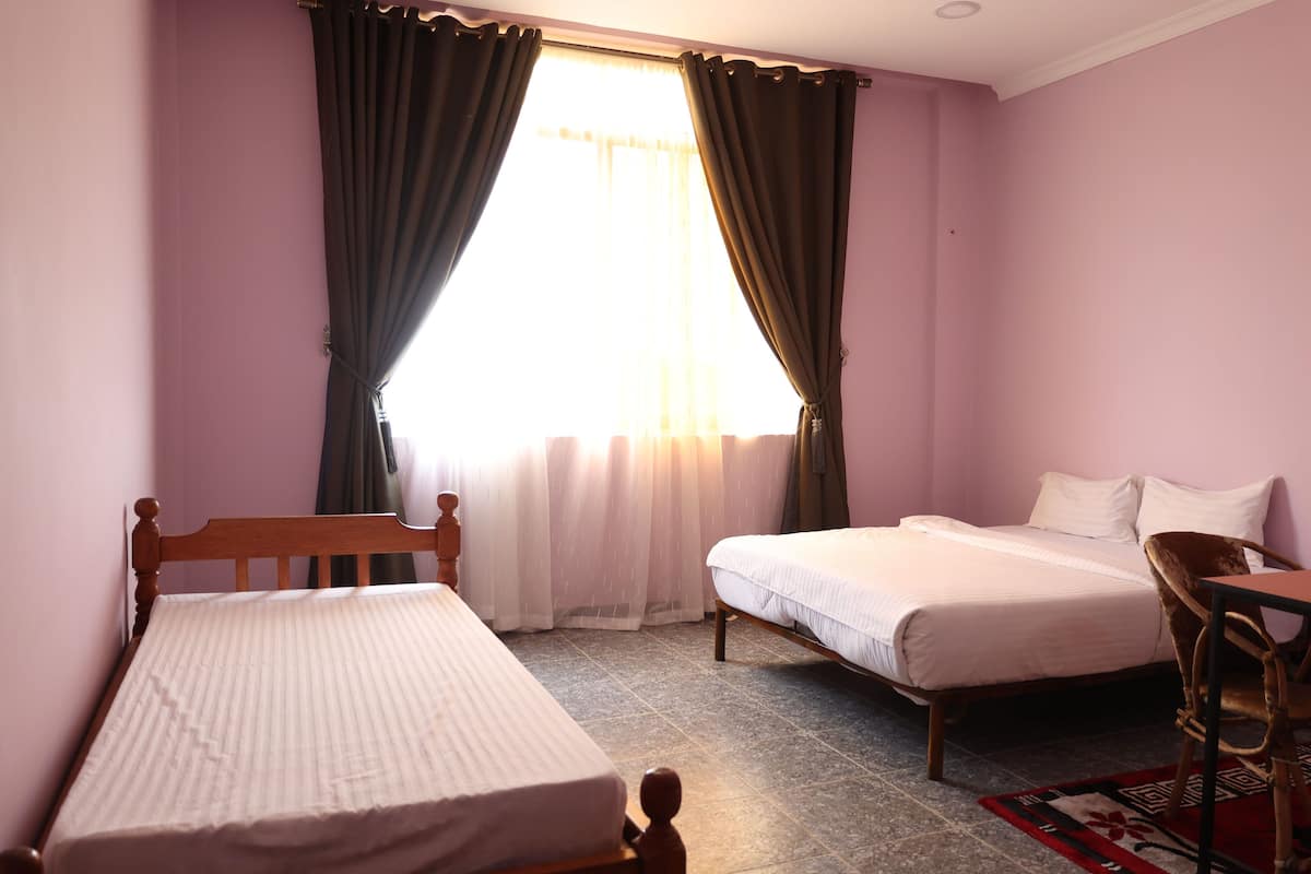 A bedroom with two single beds, a wooden headboard, a small table, and a chair.