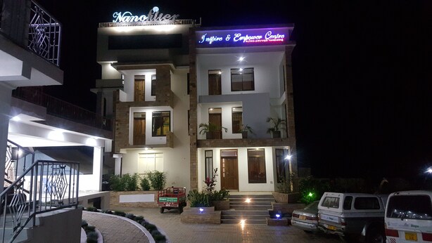 A multi-story building with a sign reading "Nanofitile Inspire & Empower Centre". - Guest House in Arusha -Nanofilter Family (Arusha)