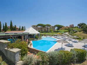 Et resort med swimmingpool, liggestole og en pavillon.