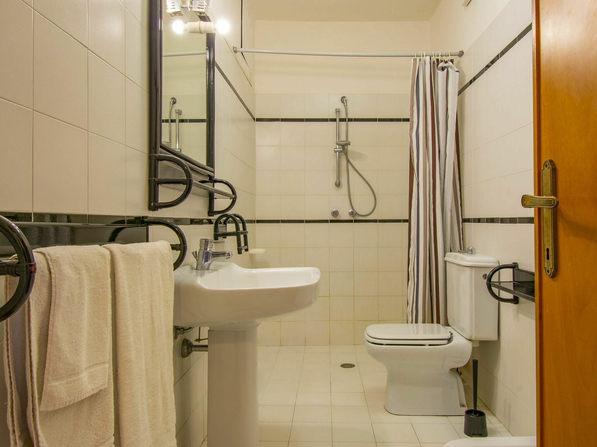 A bathroom with a sink, toilet, shower, and a mirror.