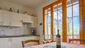 Un coin repas avec une nappe à carreaux, deux verres à vin et une bouteille de vin posée sur la table.