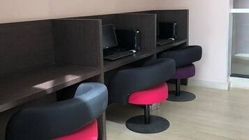 A row of individual workstations with computers and black chairs with red seats.