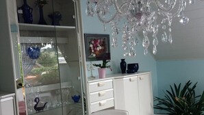 A dining area with a pink tablecloth, a crystal chandelier, and a glass display cabinet with blue vases. - Apartment for families with children, with internet access and only 800 m from the ski lift (Eibenstock)