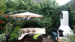 An outdoor patio with a curved sofa, a table, and a grill. - Apartment for families with children, with internet access and only 800 m from the ski lift (Eibenstock)