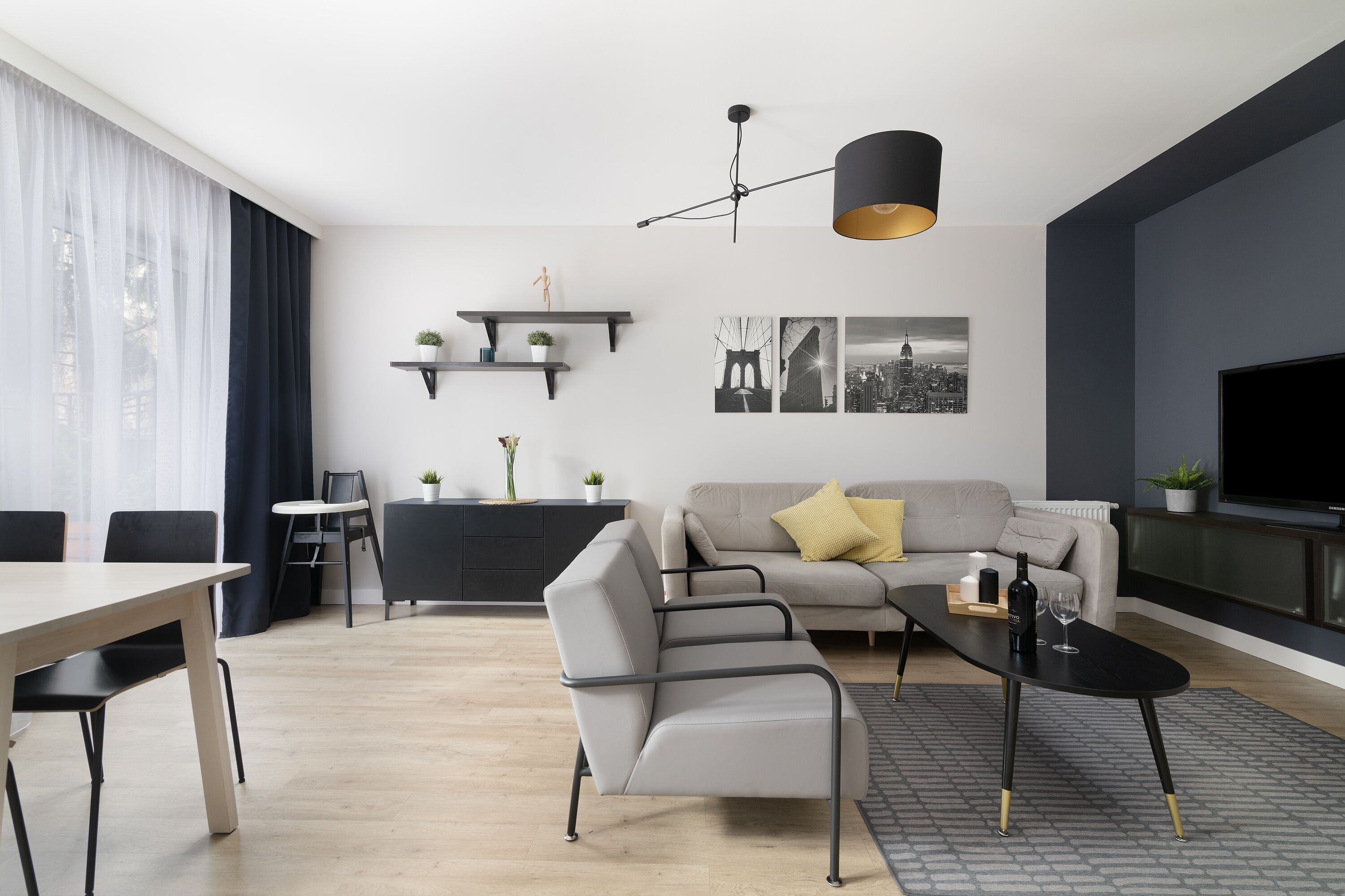 A modern living room with a sofa, a dining table, and a TV.