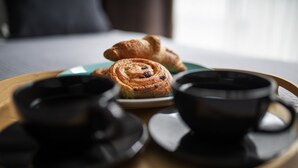 Un plateau avec des pâtisseries et deux tasses noires sur une table en bois.
