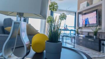 A modern living room with a sofa, a lamp, a potted plant, and a television.