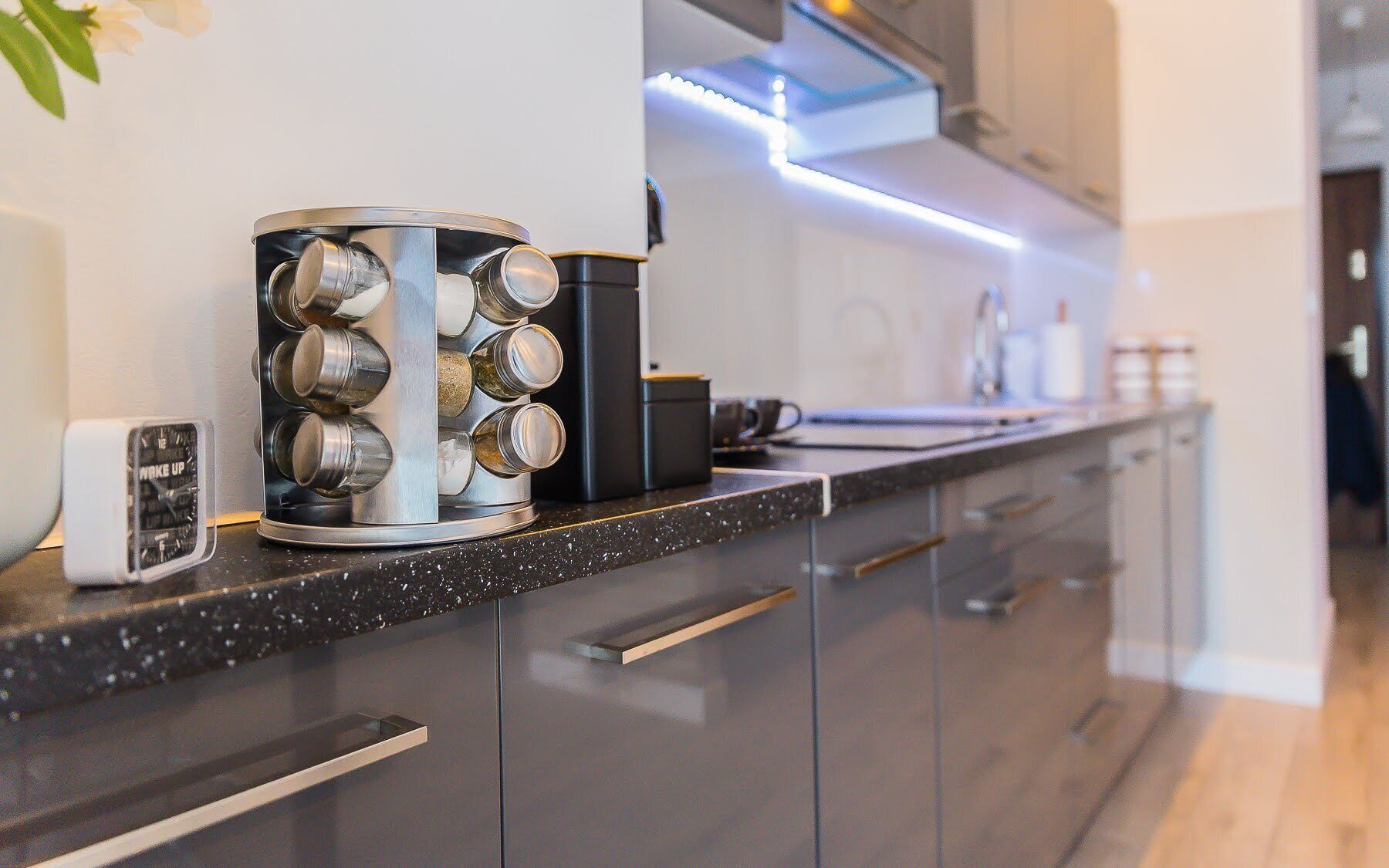 A modern kitchen with a black countertop, stainless steel appliances, and a coffee maker.