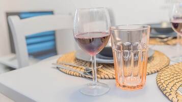 Dos copas de vino tinto sobre una mesa blanca con posavasos tejidos.