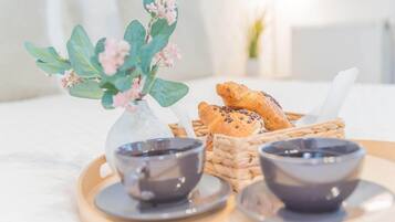 Una bandeja con dos tazas de café, un florero con flores y una cesta de pan.