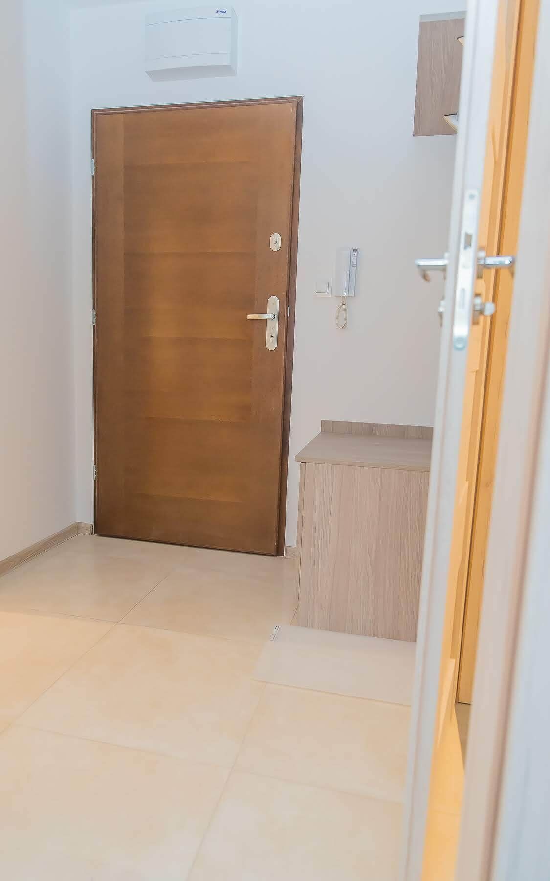 Una habitación con una puerta de madera, un pequeño banco de madera y un teléfono instalado en la pared.