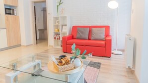 Una sala de estar moderna con un sofá rojo, una mesa de centro de vidrio y una pared de ladrillo blanco.