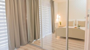 Un dormitorio con cama, mesita de noche con lámpara y espejo.