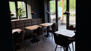 A modern restaurant interior with dark walls, wooden tables, and booths. - Moseltel Ernst/cochem (Ernst)