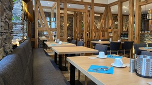 A restaurant with wooden beams, stone walls, and tables with blue placemats. - Moseltel Ernst/cochem (Ernst)