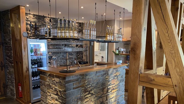 A bar area with stone walls, shelves of bottles, and hanging lights. - Moseltel Ernst/cochem (Ernst)
