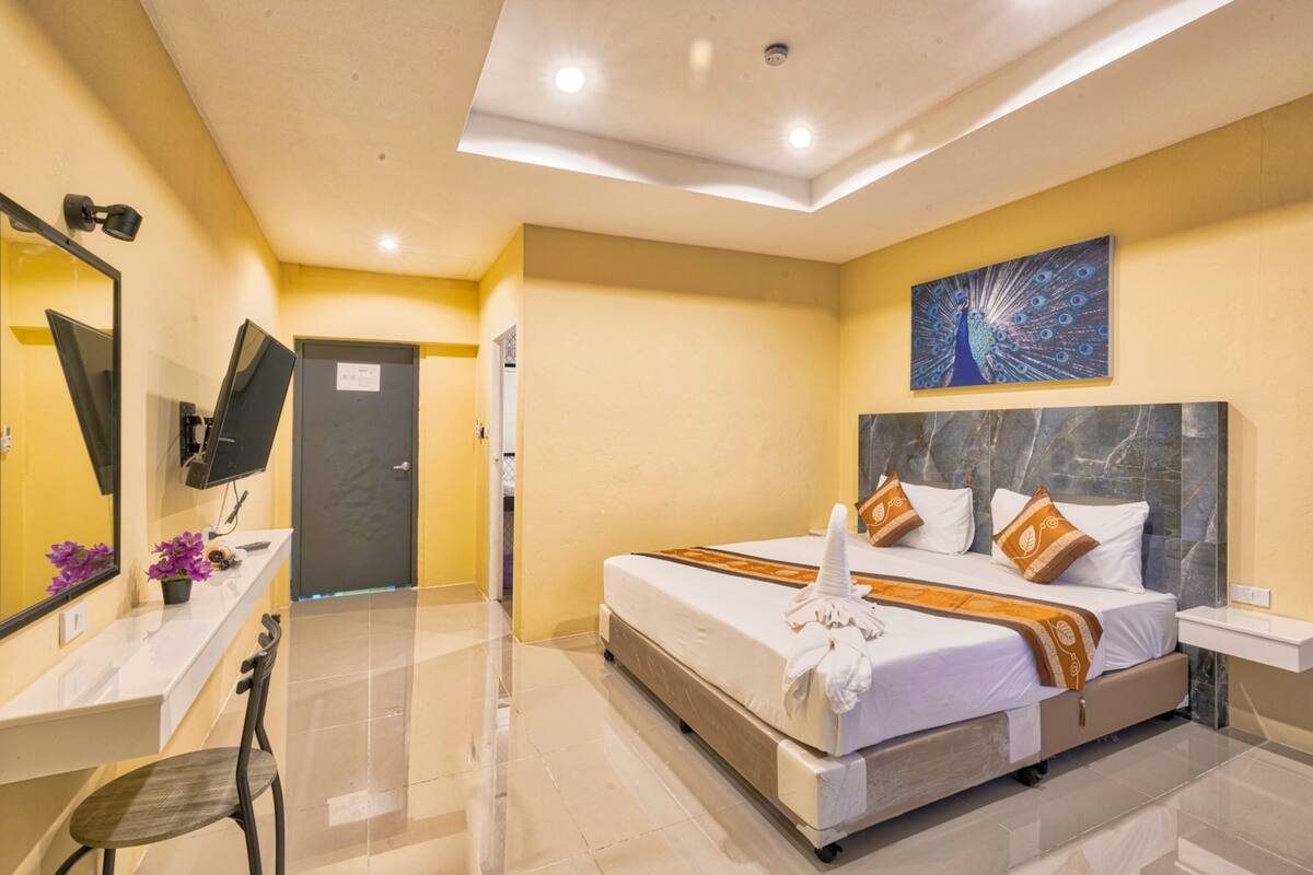 Une chambre d’hôtel avec un grand lit, un téléviseur à écran plat, un bureau avec une chaise et une porte de salle de bain.