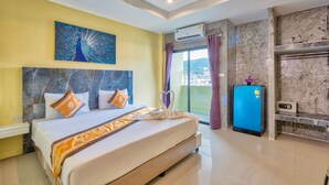 A hotel room with a large bed, a peacock painting, a minibar, and a view of the city. - TJ PATONG HOTEL - Prime Location by OTOP Market & Sea (Patong)