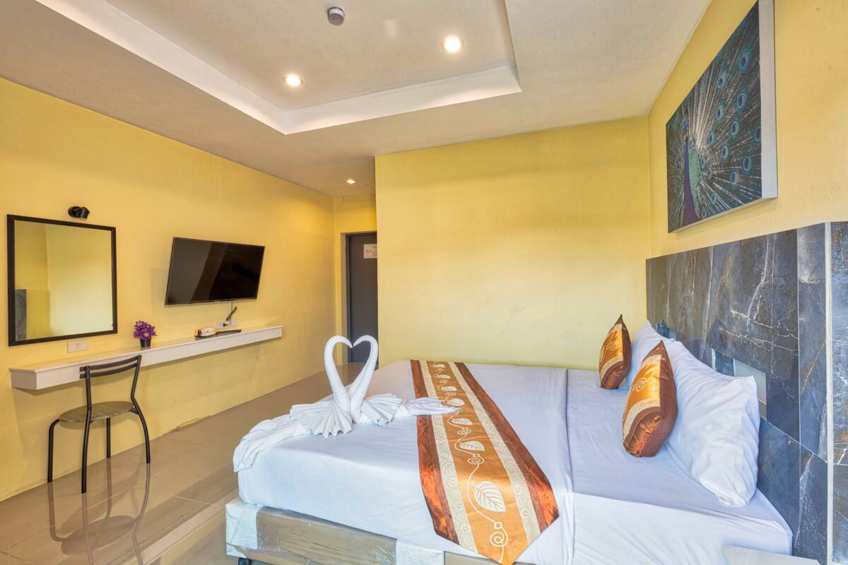 Une chambre d’hôtel avec un lit, une télévision, un miroir et une chaise.