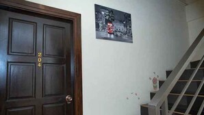 A dark wooden door with the number 204, a staircase with glass railings, and a black and white photograph on the wall. - TJ PATONG HOTEL - Prime Location by OTOP Market & Sea (Patong)