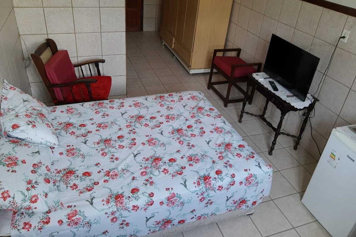 Un dormitorio con cama, televisor, una mesita y un armario.