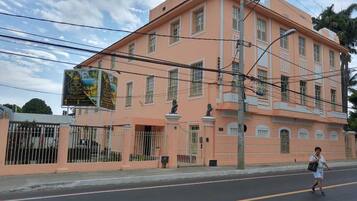 Um edifício rosa com várias janelas e entrada protegida por grades.